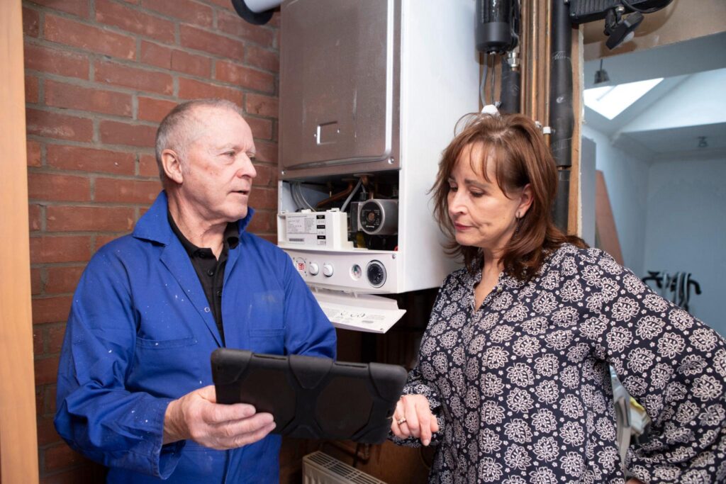 Gas Engineer Talking To Customer About Boiler Service